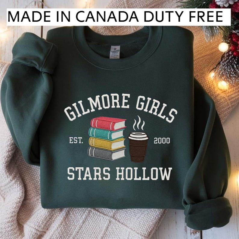 A dark green sweatshirt with a graphic design featuring a stack of books and a cup of coffee, along with text that reads "GILMORE GIRLS EST. 2000 STARS HOLLOW".