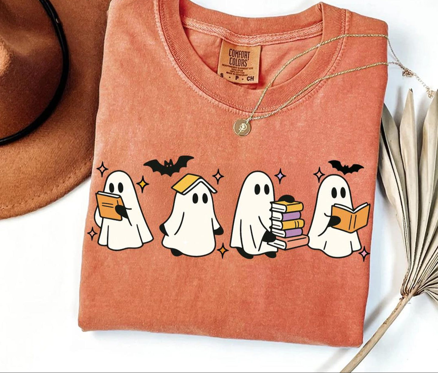 Folded orange t-shirt with ghost illustrations on a white background