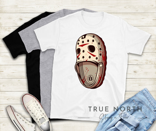A graphic design of a hockey mask on a white t-shirt, displayed alongside a gray t-shirt, a pair of white sneakers, and blue jeans. The design features a red and beige color scheme with a stylized letter 'J'.