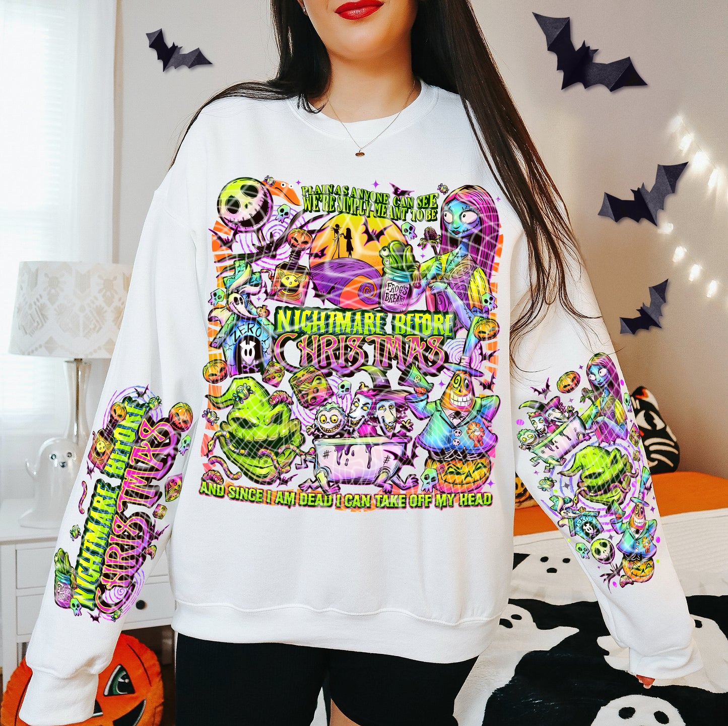 Person wearing a white sweatshirt with colorful ' design, surrounded by Halloween decorations.