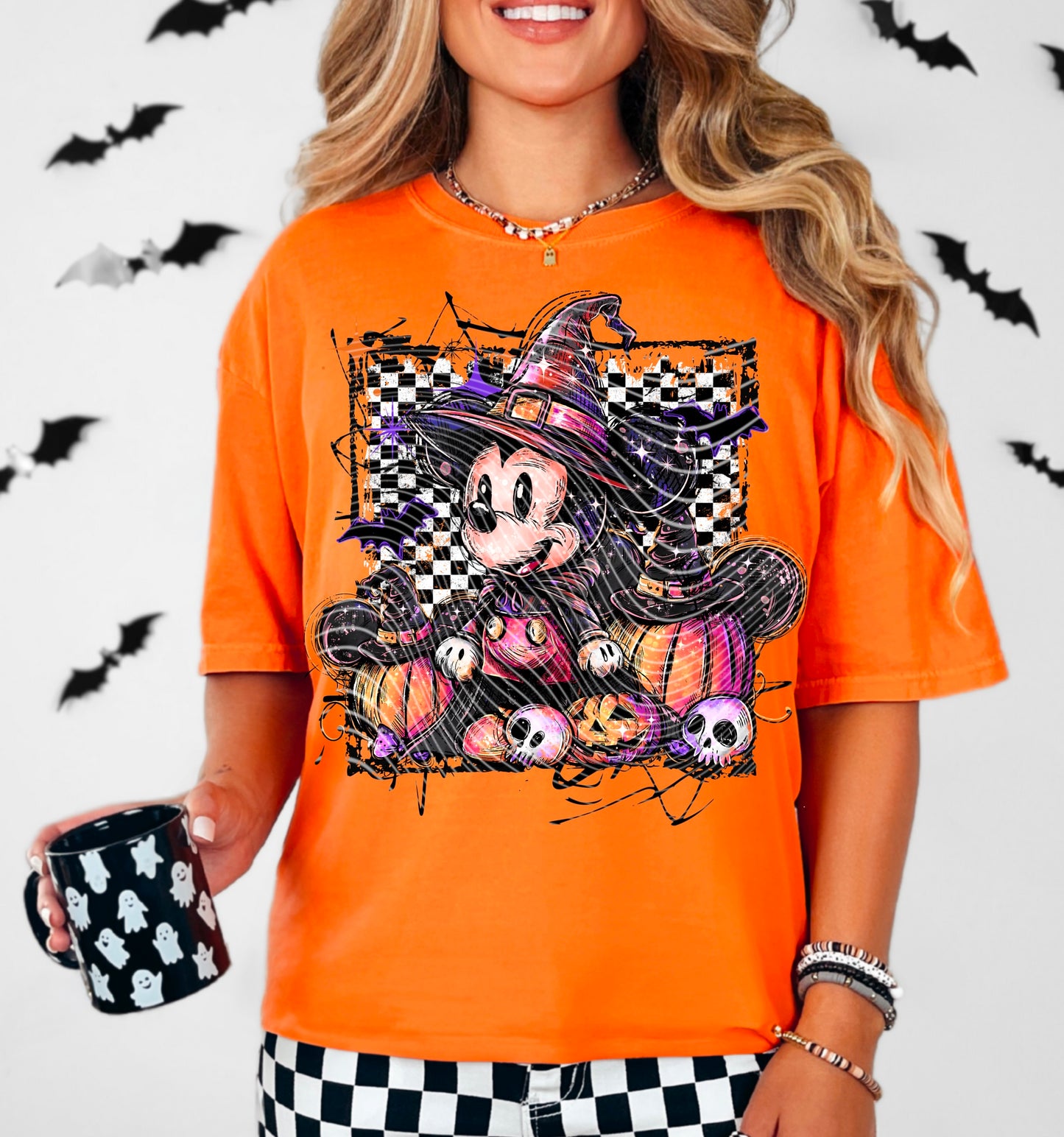 Person wearing an orange Halloween-themed t-shirt with a cartoon character, holding a black mug with ghost patterns, against a white background with black bats.