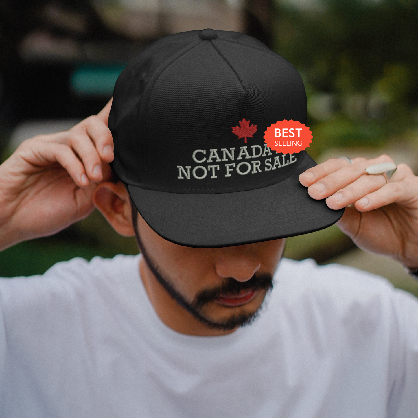 a man adjusts his hat with the canada not for sale sticker on it