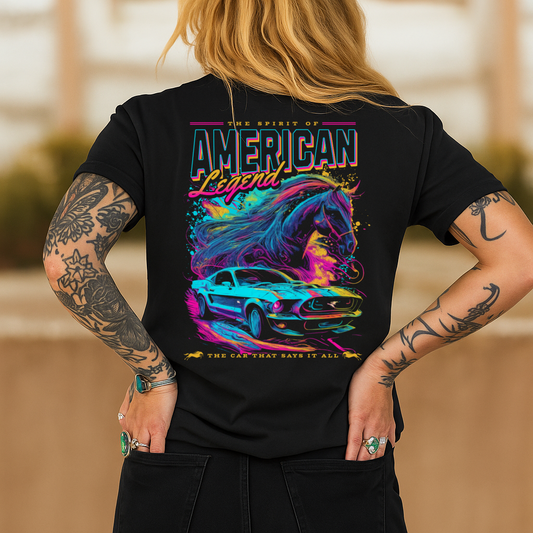 Person wearing a black t-shirt with a colorful graphic design of a car and horse, with text 'The Spirit of American Legend'.