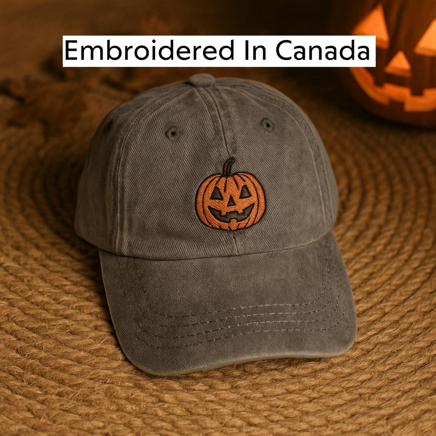 A gray baseball cap with a pumpkin embroidered on it, placed on a woven surface.