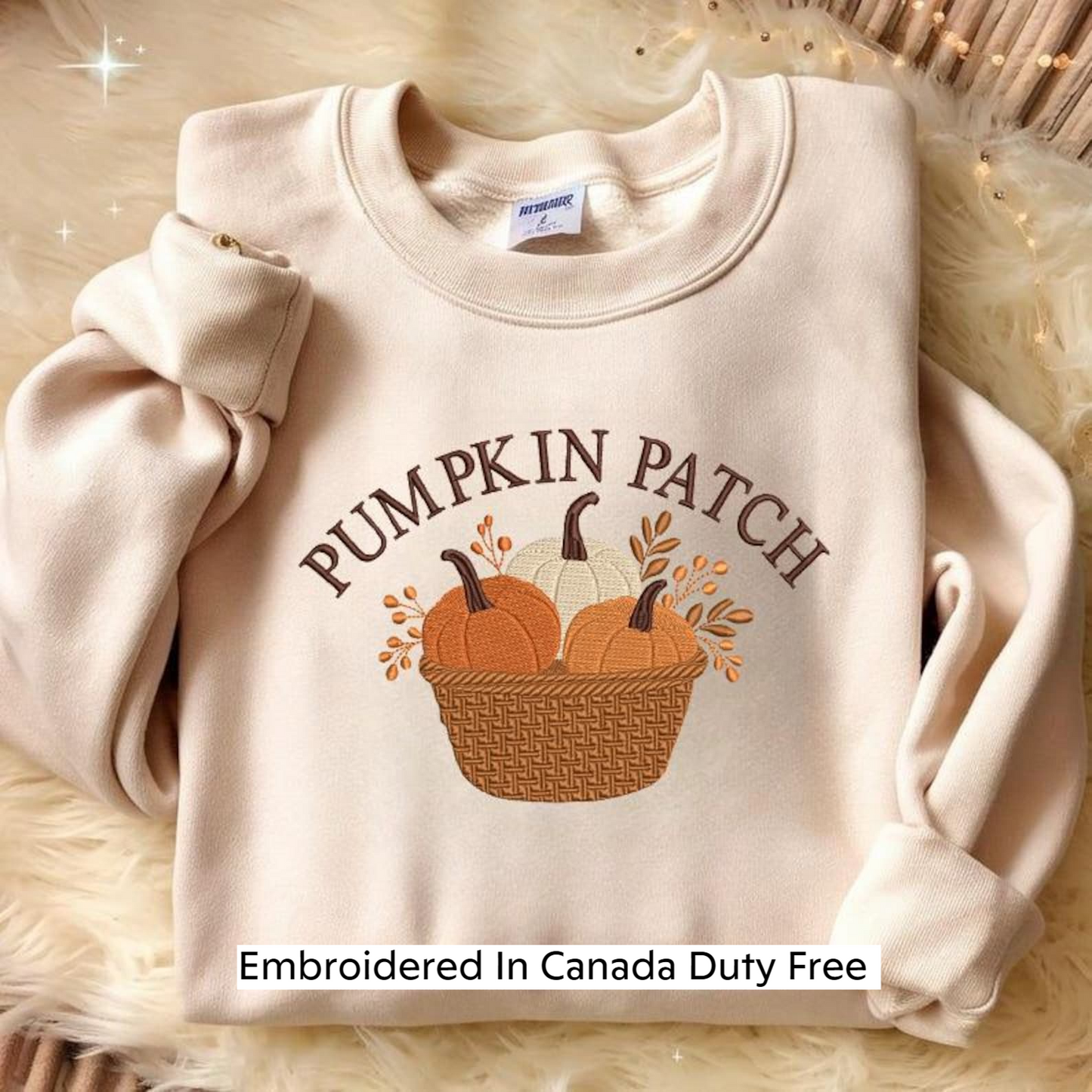 A beige sweater with a pumpkin patch design and the text "PUMPKIN PATCH" embroidered on it, along with the text "Embroidered In Canada Duty Free" at the bottom.
