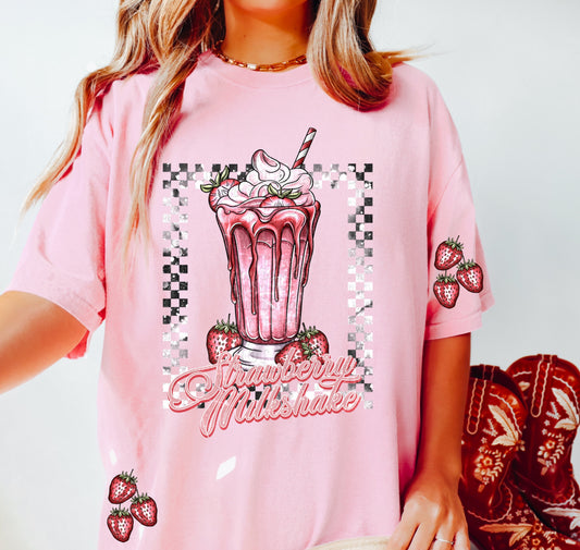 a woman in a pink shirt holding a strawberries milkshake