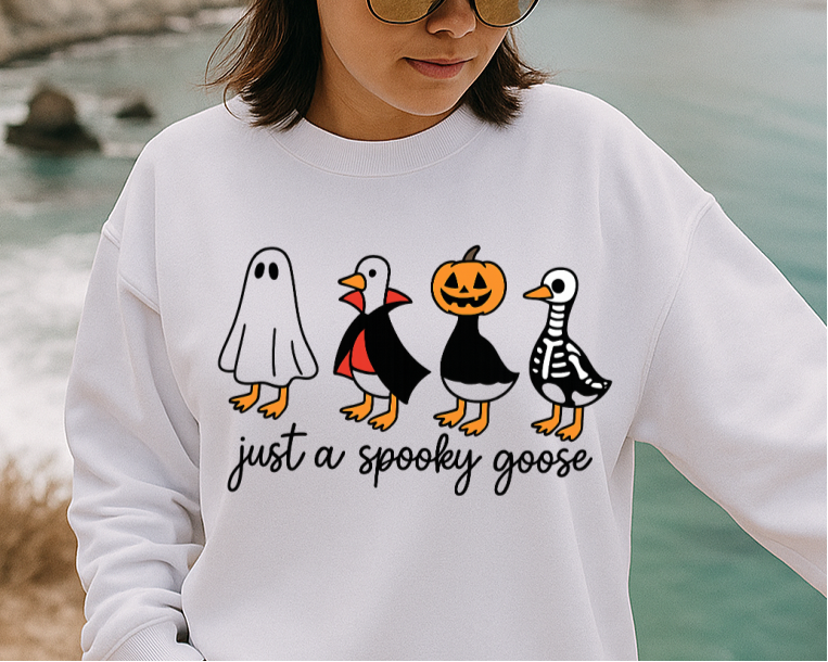 Person wearing a white sweatshirt with a graphic design by a body of water.
