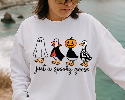 Person wearing a white sweatshirt with a graphic design by a body of water.