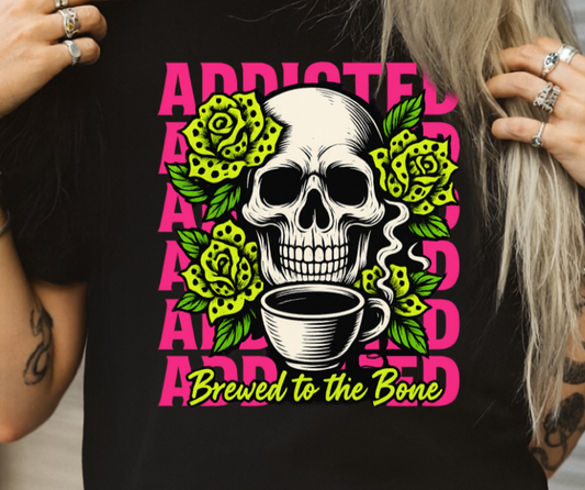 Person wearing a black t-shirt with a skull and coffee design, text 'Addicted Brewed to the Bone'.