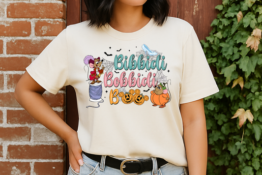 Person wearing a white t-shirt with colorful graphics and text, standing against a brick wall with greenery.