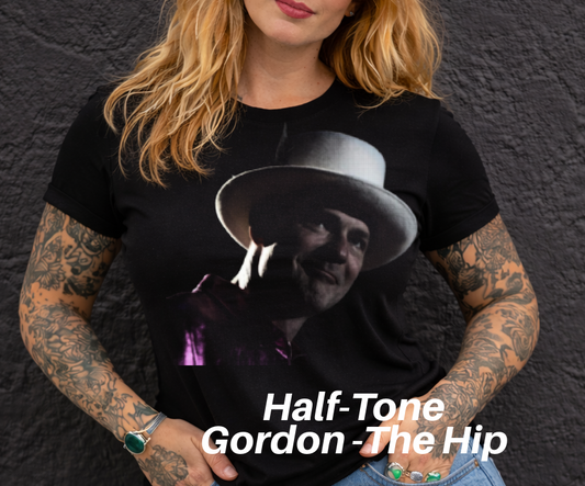 A woman with long blonde hair wearing a black t-shirt with a graphic of a man wearing a hat.
