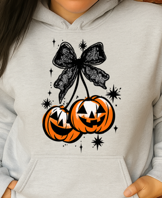 Person wearing a light gray hoodie with Halloween-themed design against a brick wall.