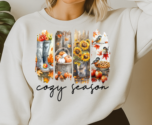 Woman wearing a white sweatshirt with autumn-themed design and text 'cozy season'.