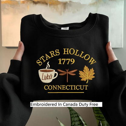 A person is holding up a black sweatshirt with embroidered text and images on it.