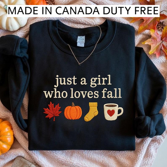 A black sweatshirt with a text design on it, along with various fall-themed items such as a pumpkin, a mug, and a leaf, all placed on a blanket with autumn leaves.