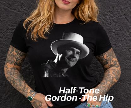 A woman with long blonde hair wearing a black t-shirt with a black and white portrait of a man wearing a hat.