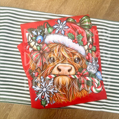 Festive Highland cow wearing a Santa hat and surrounded by Christmas bows, ornaments, snowflakes and candy cane. The original photo is multicolour; the Black and White choices refer to the ordered colour version.