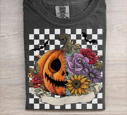 Gray t-shirt with a Halloween-themed design featuring a pumpkin, flowers, and bats on a checkered background.