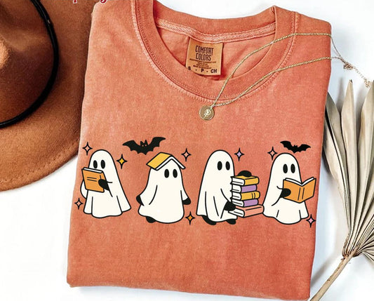 Folded orange t-shirt with ghost illustrations on a white background