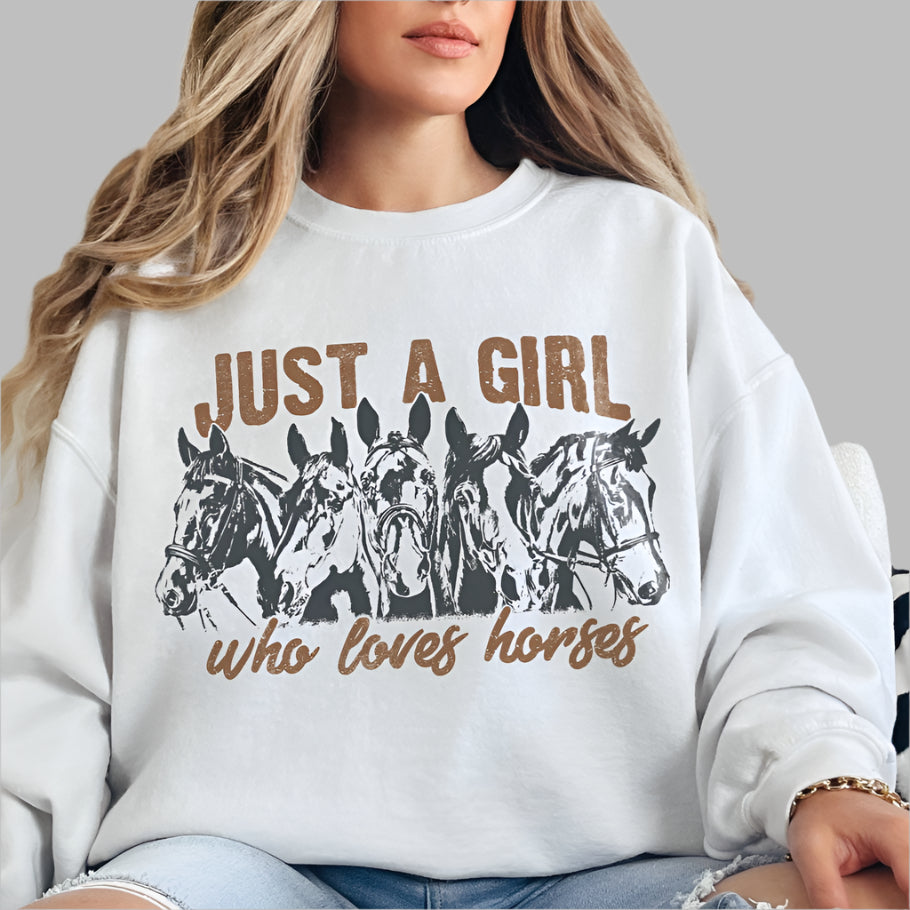 A woman wearing a white sweatshirt with a graphic print of horses and the text 'JUST A GIRL who loves horses'.