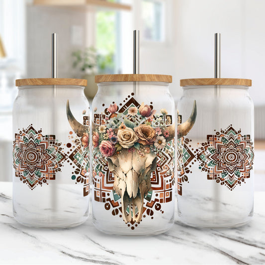 Three glass tumblers with cow skull and floral design on a marble surface.