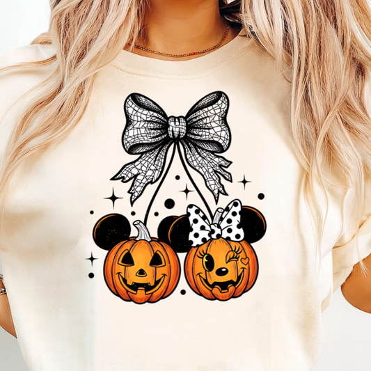 Person wearing a white t-shirt with Halloween-themed design featuring pumpkins and bows.