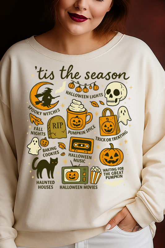 Woman wearing a cream-colored sweatshirt with Halloween-themed graphics against a dark background.