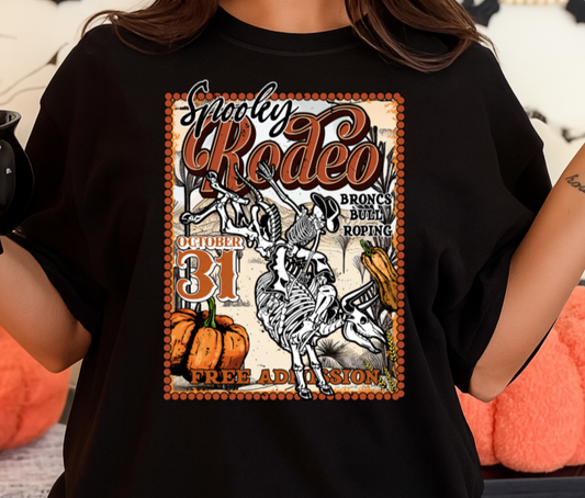 Person wearing a black t-shirt with a rodeo graphic design, holding a mug in a Halloween-themed setting.