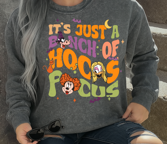 Person wearing a gray sweatshirt with colorful text and cartoon characters, sitting on steps.