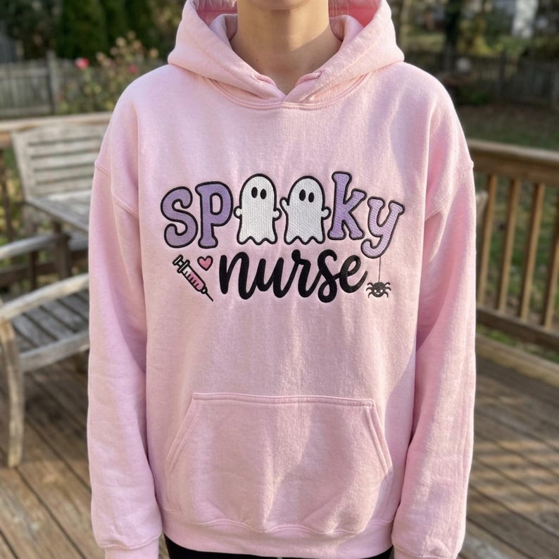 Spooky Nurse embroidery design worn on a finished pink hoodie outdoors